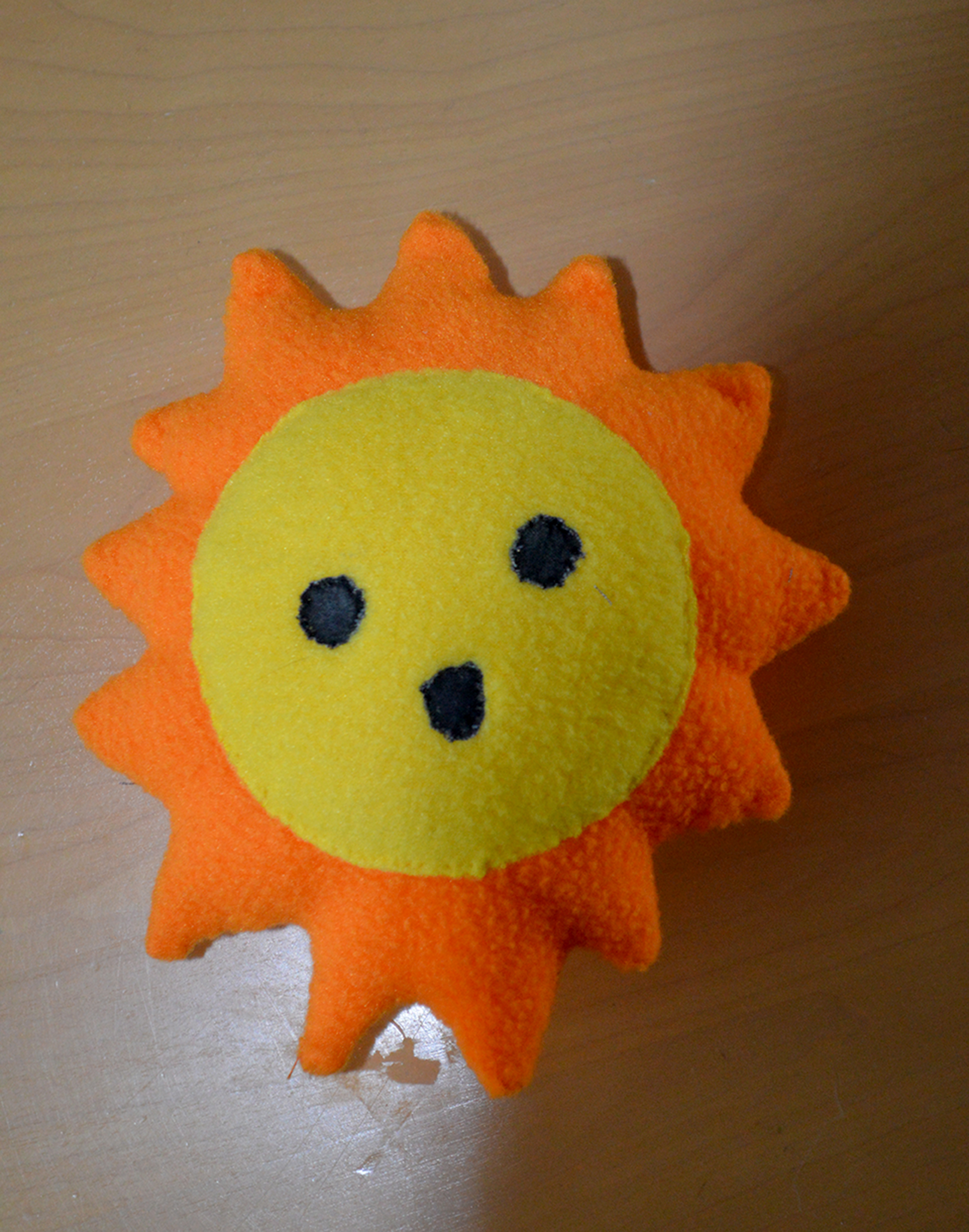 a plush toy shaped like a sun with a smiling face