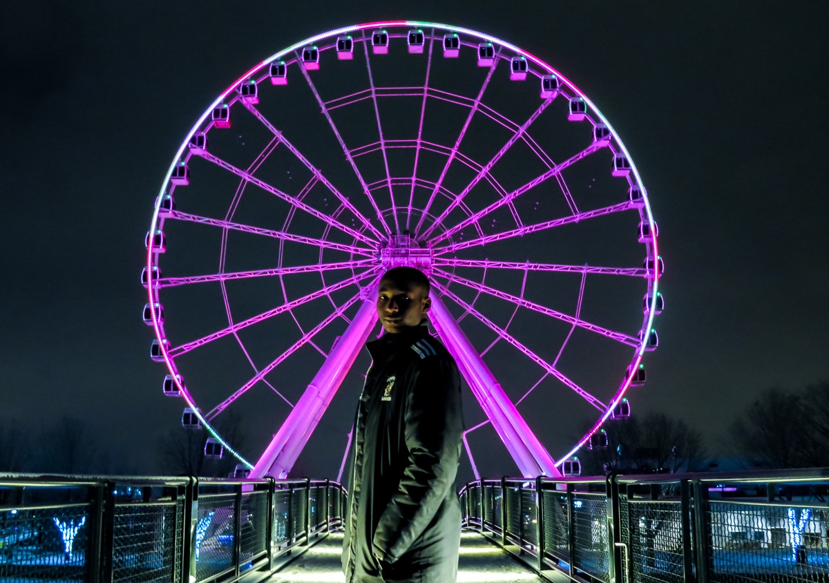 Creative photograph of a man in front of a lit up ferris wheel